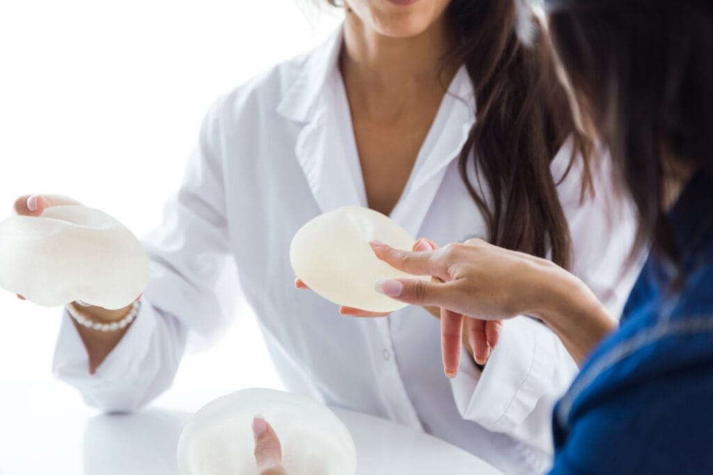 doctor-her-patient-choosing-mammary-prosthesis-office-min