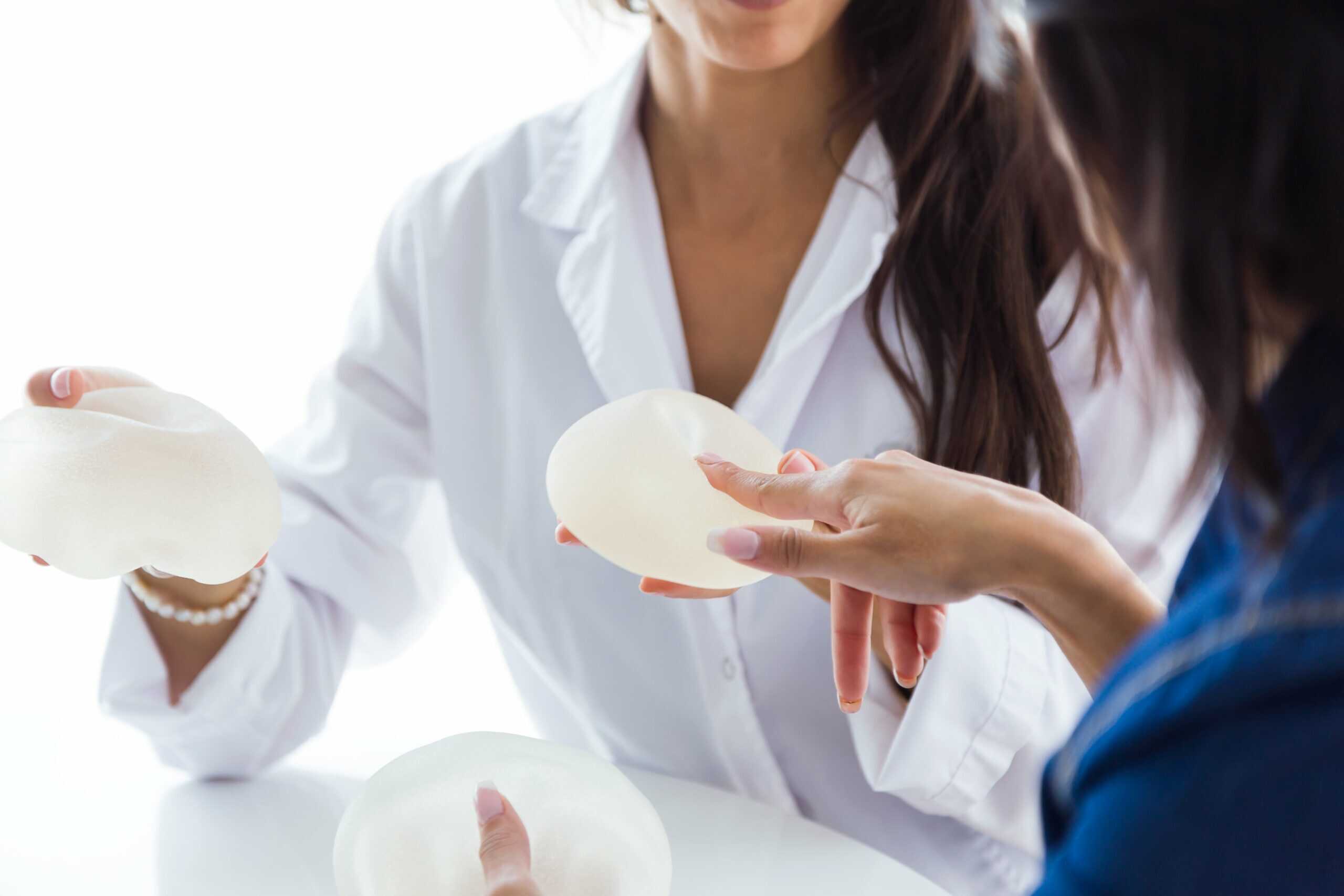 doctor-her-patient-choosing-mammary-prosthesis-office-min